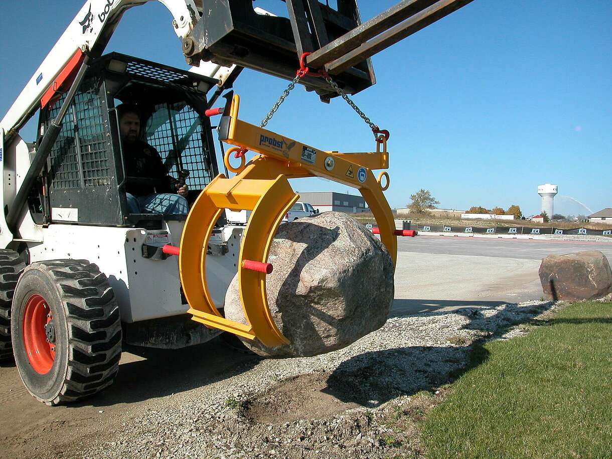 Heavy machinery is shown lifting a rock outside. It displays the importance of using heavy equipment for larger projects.