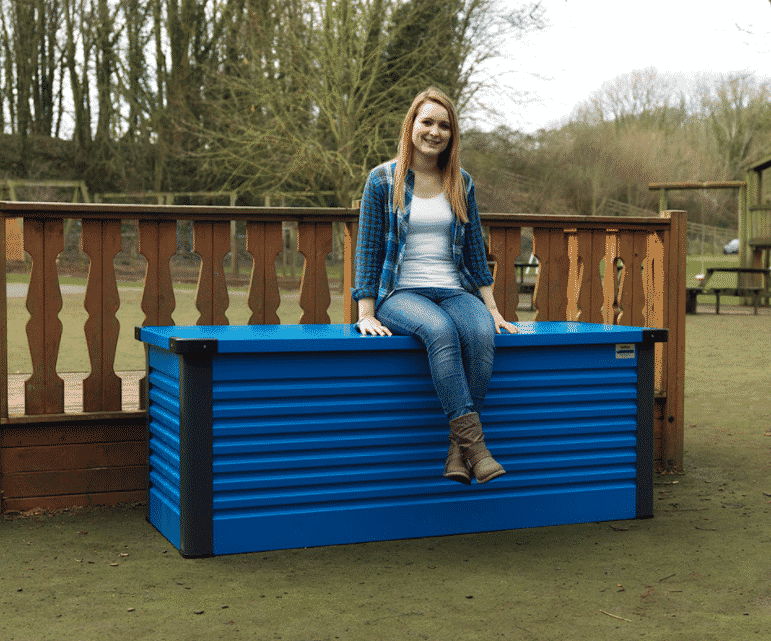 Someone sitting on a patio storage box to show its durability.